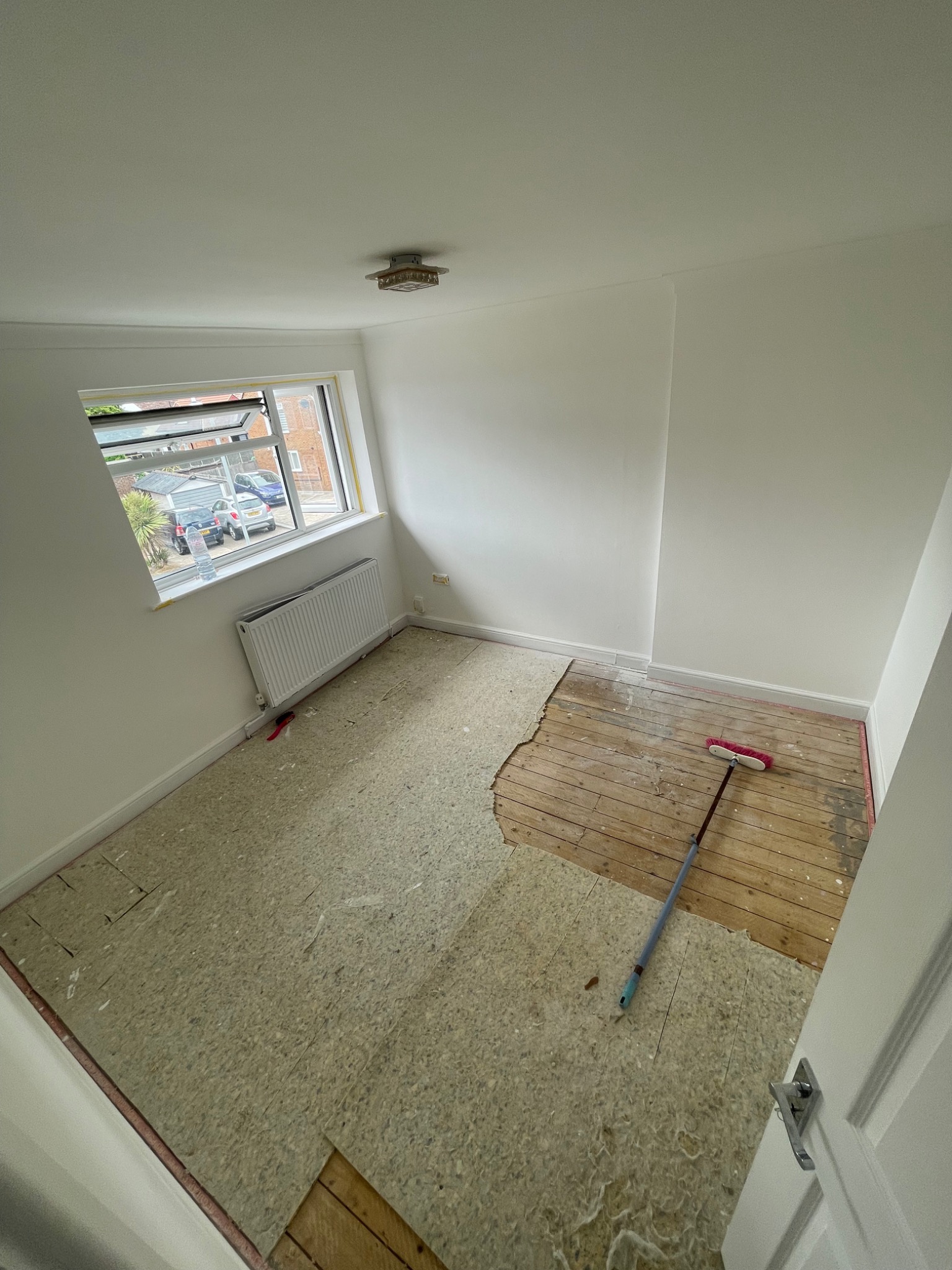 Before: an empty bedroom with exposed floorboards and underlay before the final fit-out.