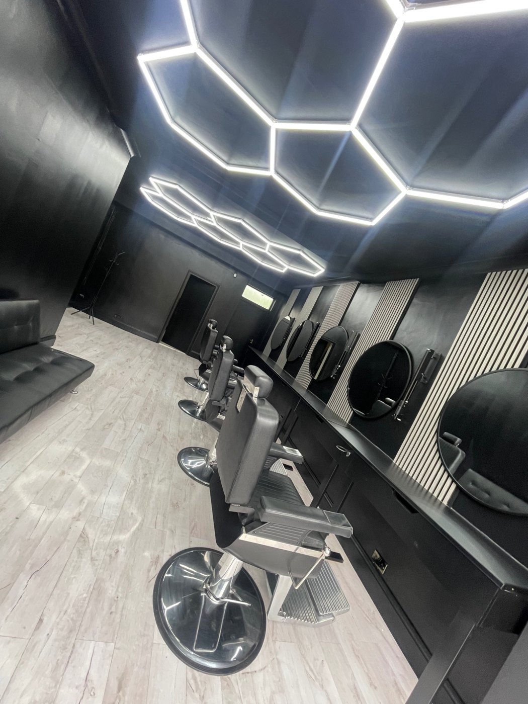 After: Completed barbershop with styling stations, chairs and geometric ceiling lighting.