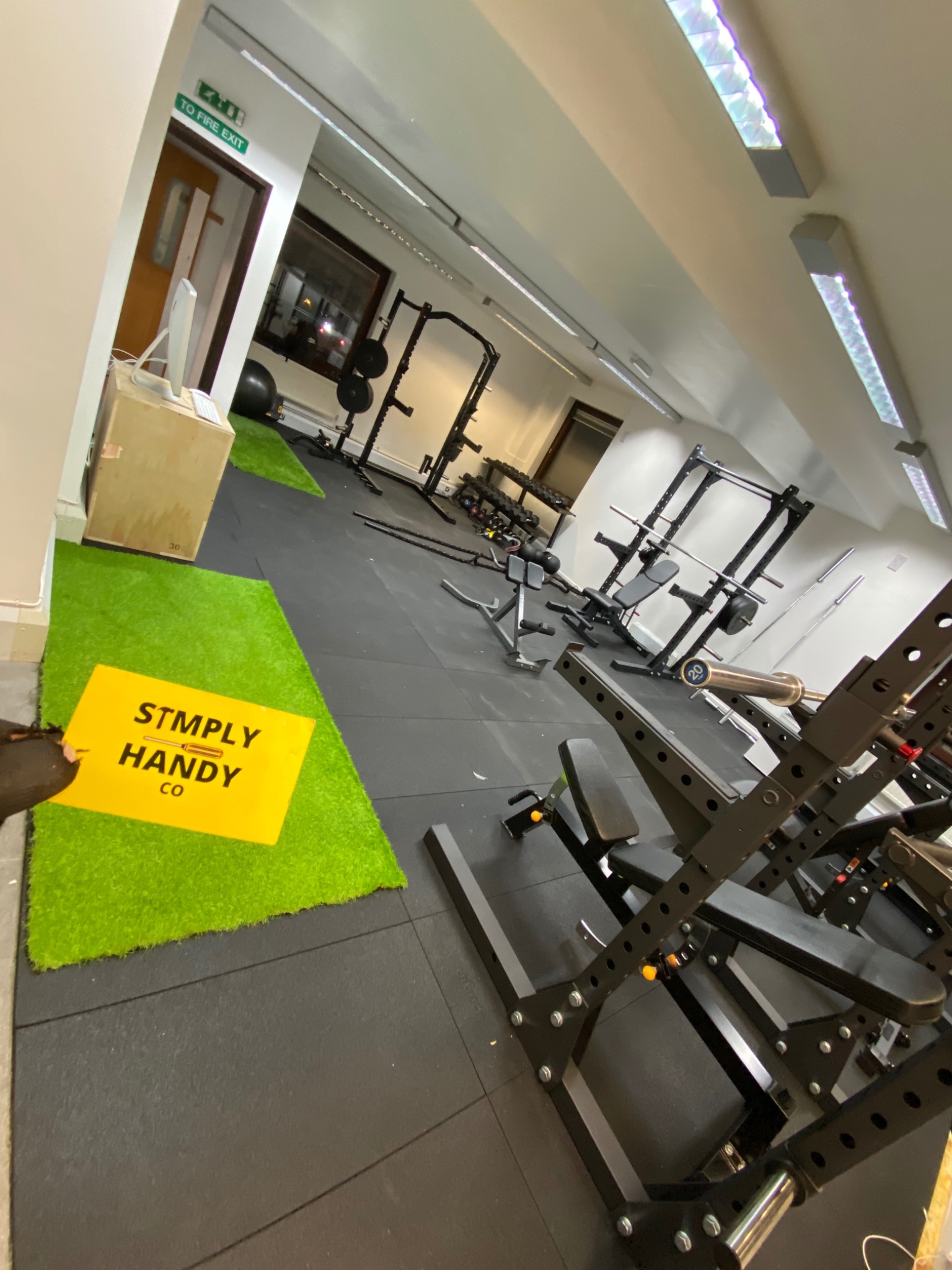 After: the gym with continuous rubber flooring, green turf zones and equipment arranged for use.