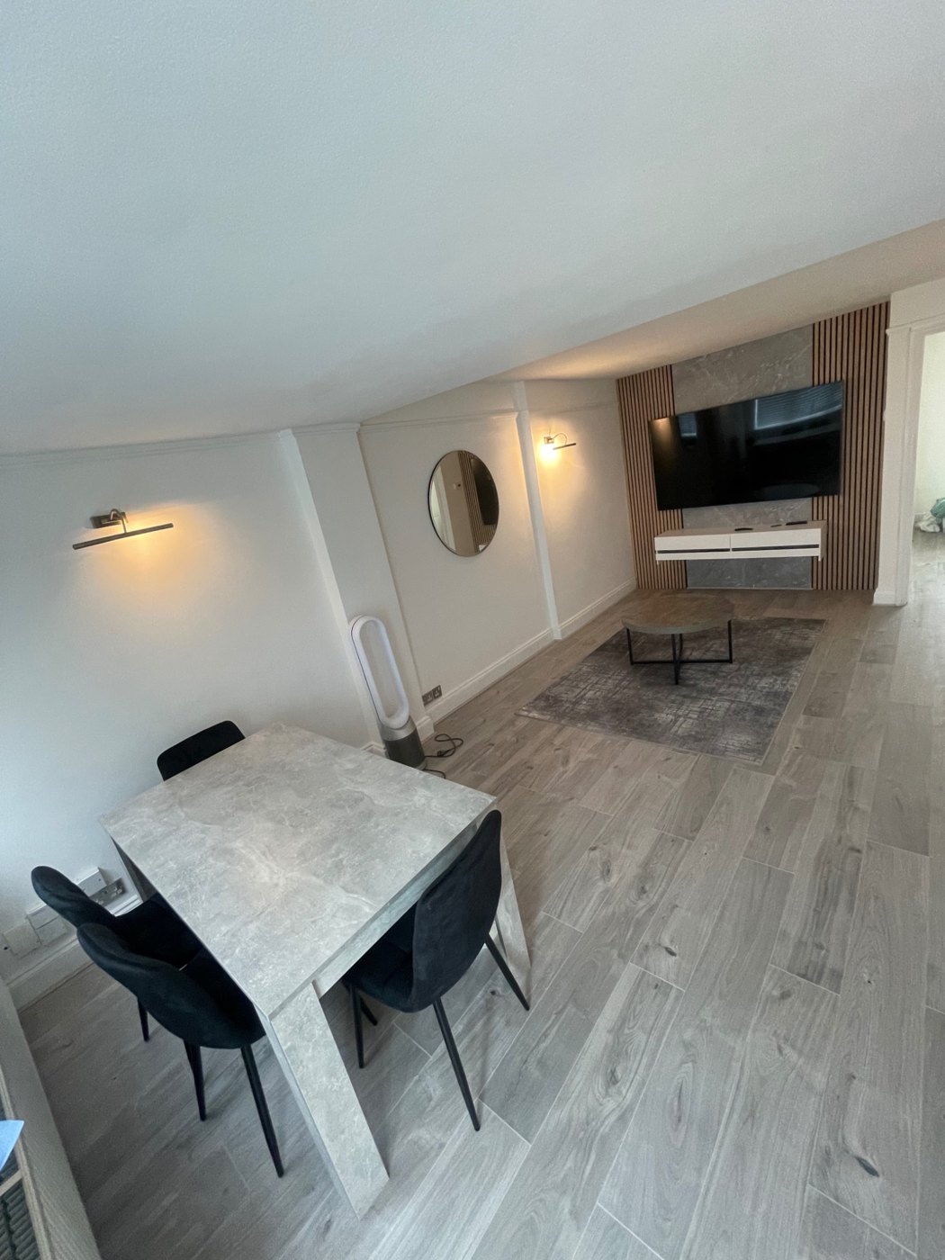 After: Finished living and dining area with flooring, wall lights and a media feature.