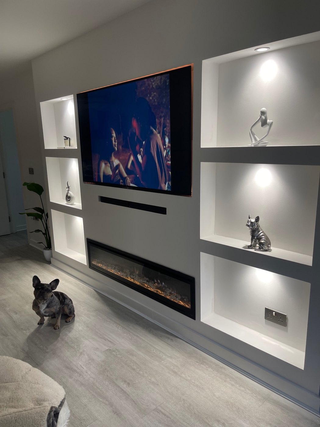 After: Built-in media wall with a television, illuminated display shelves and a fireplace.